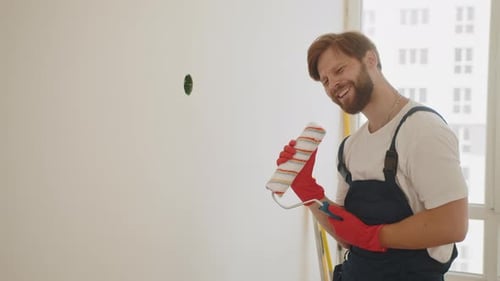 Man Singing While Painting Wall in Bright Room