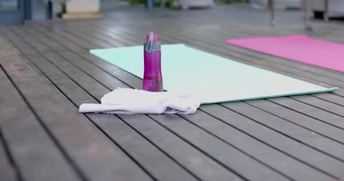 Water bottle, towel and exercise mats on sunny terrace