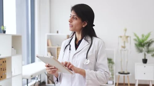 Therapist holding tablet while posing in doctor's office