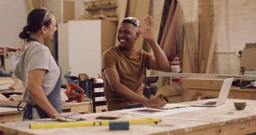 4k video footage of two designers giving each other a high five while working in a workshop