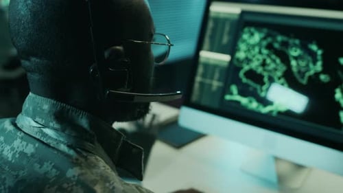 Intense Man Works at Computer With Headset