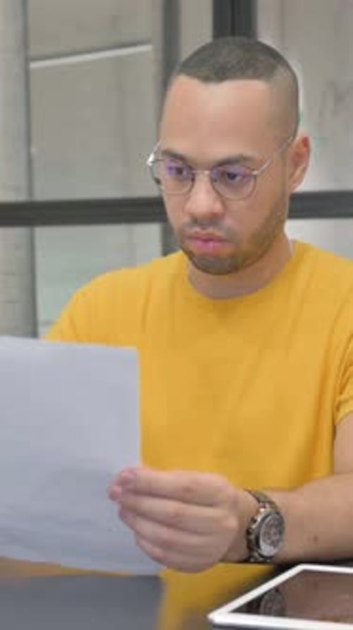 Man Reviews Documents with Concerned Expression in Office