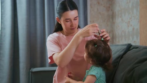 Woman Brushing Daughter's Hair at Home on the Couch