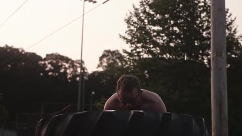 Man flipping large tire towards camera for exercise from front, Medium Close Up, Slow Motion