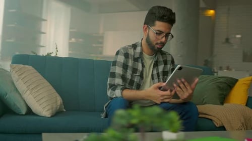 Young Adult Using Tablet on Couch at Home