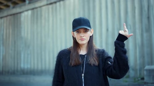 Une fille sérieuse montre un signe de paix puis un geste offensant dans la rue de la ville