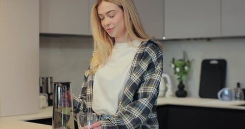 Woman Pours Water in Modern Kitchen