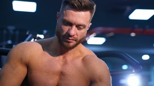 Athlete with strong body poses on modern gym background. View from the bottom.