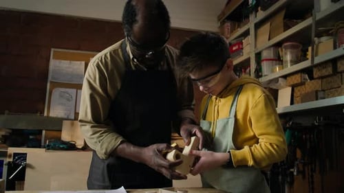 Boy Learning Woodworking Craft with Assistance from Adult