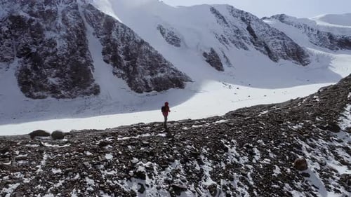 Ein Mann in Schneeschuhen und Trekkingstöcken in den Bergen Winterausflug Klettern eines Bergsteigers gegen einen