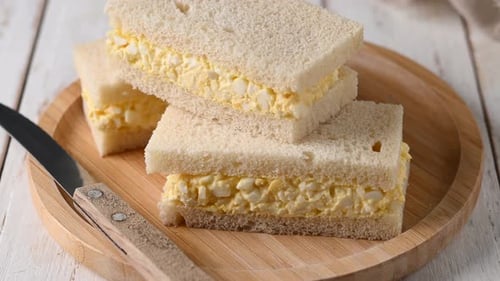 Stacked Egg Salad Sandwiches on Wooden Plate