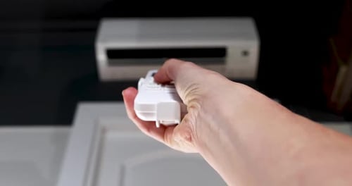 Woman Turning on the Air Conditioner