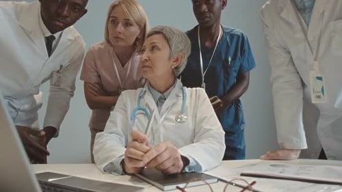 Medical Team Collaborating at Desk with Laptop