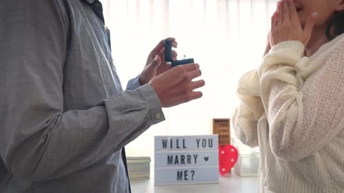 Close up of romantic man surprise girlfriend with a marriage proposal.