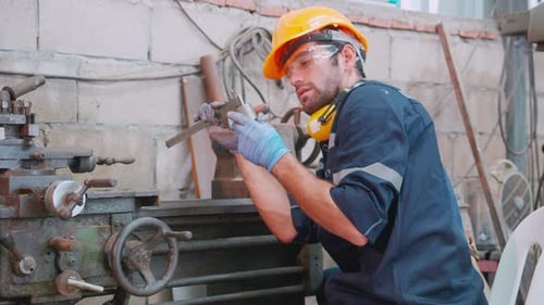 Young caucasian engineer man operating lathe machine for preparing production at factory industrial.