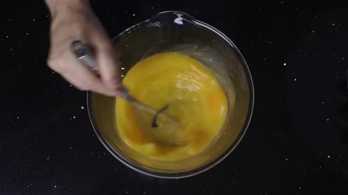 Topdown view of whisking eggs in a bowl.