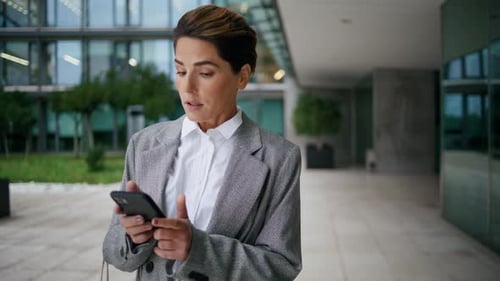 Woman using phone outside modern office building