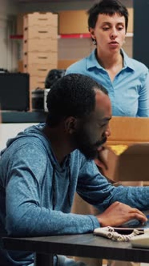 Colleagues Collaborating on Laptop in Warehouse Office