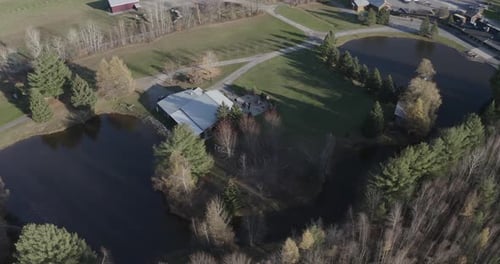 Drone aerial clip of a beautiful acreage property with a large pond and a bunch of old buildings in