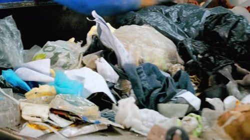 Employee working with garbage moving on a conveyor belt at waste sorting plant