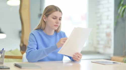 Woman Reviews Papers, Makes Notes in Office