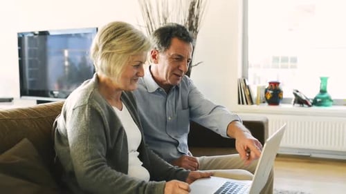 Senior Couple Using Laptop Together in Bright Living Room