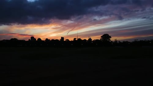 Wolken bewegen sich bei einem atemberaubenden Sonnenuntergang über der Silhouette eines Stadtbildes