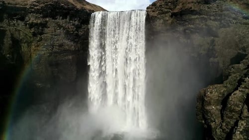 Powerful Majestic Waterfall Cascading Down Dark Rocky Cliffs Into Mist