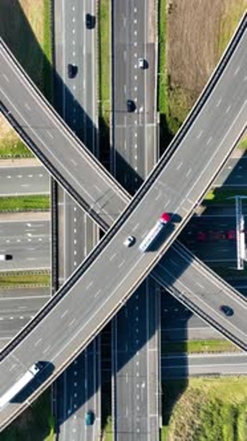 Vertical aerial top-down view of a multi-level highway interchange with busy car traffic