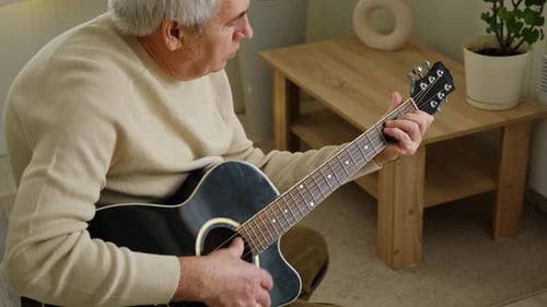 Senior Man Playing Acoustic Guitar at Home