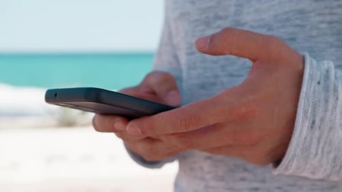 Hands Using Smartphone on a Beautiful Beach