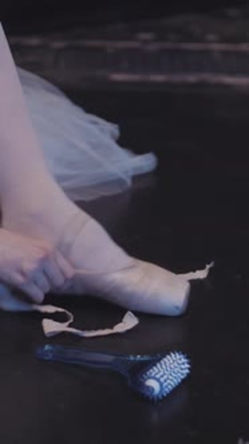 Close up shot of a ballerina putting on her pointe shoes. Graceful ballet dancer tying shoes up