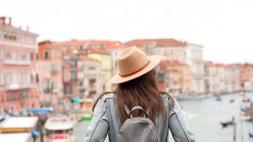 Tourist woman with hat looking at Grand Canal from Ponte Rialto, Venezia
