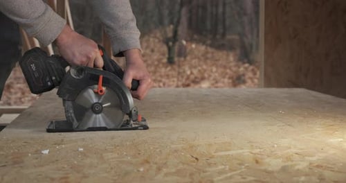 Closeup of a Worker Using a Circular Saw to Cut Plywood