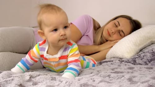 Baby Crawling as Mother Sleeps Peacefully at Home