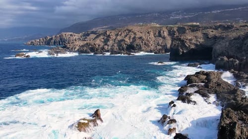 Bird's Eye View of Ocean Waves Crashing Against Stone Cliffs on Tenerife Island