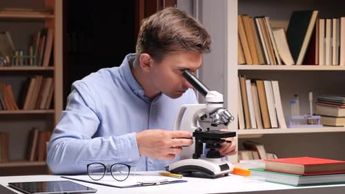 Young Man Using Microscope in Home Laboratory