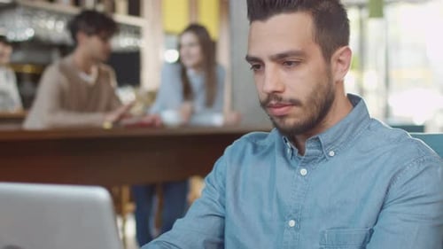 Hispanic Ethnicity Young Man using Laptop Computer at Cozy Coffee Shop.