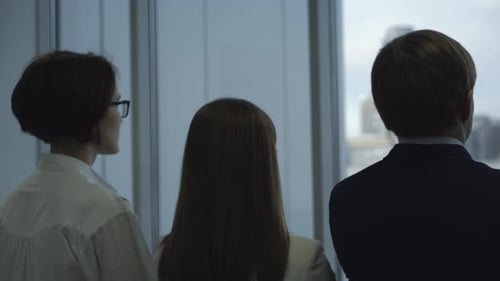 Business People Looking Out Office Window at City View