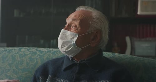 Senior Adult Wearing Face Mask Sitting on Couch