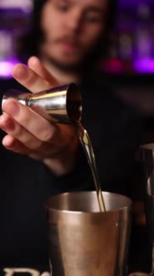 The bartender makes cocktails behind the bar counter.