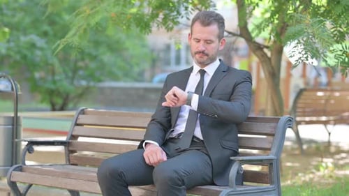 Man in Suit Waiting in Park, Checking Watch