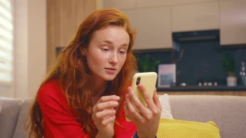Young Woman Using Phone While Relaxing on Sofa