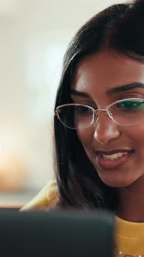 Young Woman Smiling While Looking at Tablet Indoors