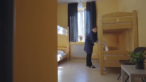Female Housekeeper Changing Bedding in a Hotel Room