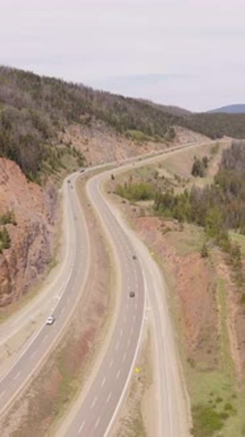 Aerial View of Winding Highway with Vehicles Traversing Through the Majestic Mountains