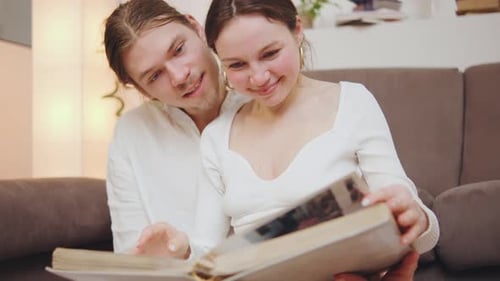 Smiling Couple Reminiscing While Looking at Photo Album