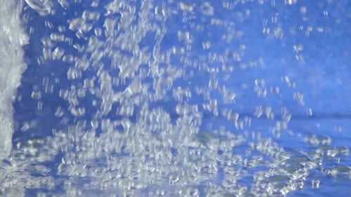 Water Stream and Bubbles Against Blue Backdrop