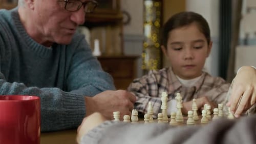 Grandfather Teaching Grandchildren Chess Game at Home