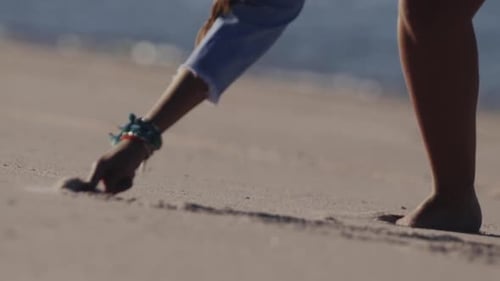 Detail of a woman hand writing on beach sand